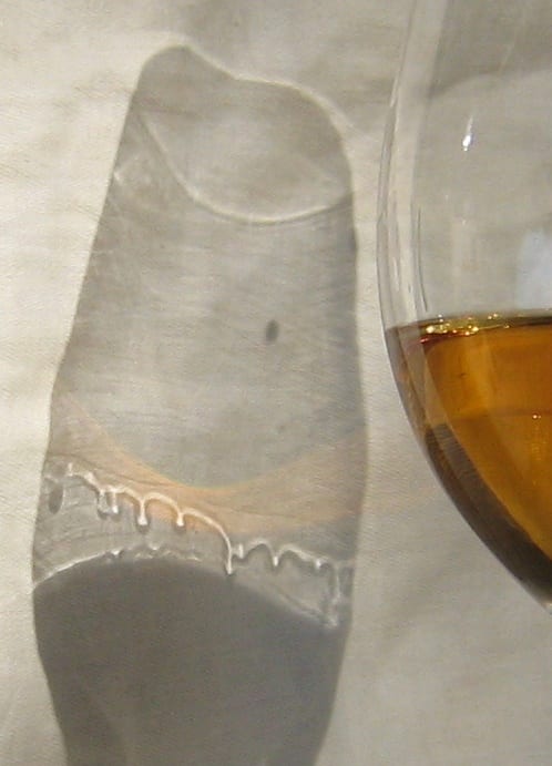 Legs cast in the shadow beside a glass, droplets forming on the wall and running down