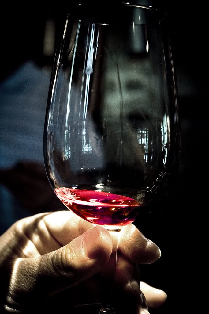 A hand swirling a tasting glass against a dark background